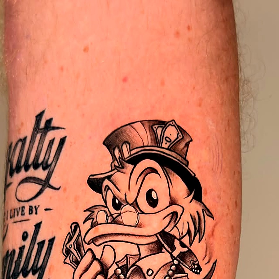 Black and grey character tattoo on a shin — top hat and money