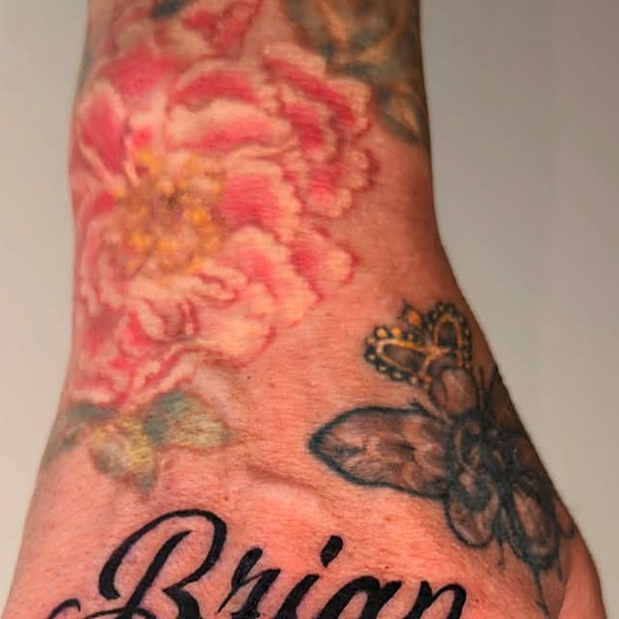 Color floral hand tattoo — pink peony with a black flower